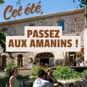Bâtiment des Amanins avec groupe de personnes assises dans l'herbe en été